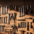Dozens of hand tools arranged neatly on a workshop pegboard, every tool in its own place, lit by warm directional side light
